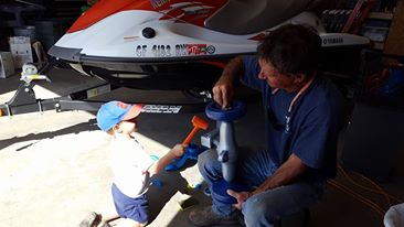 Karl Pflum fixing a part while his grandson helps
